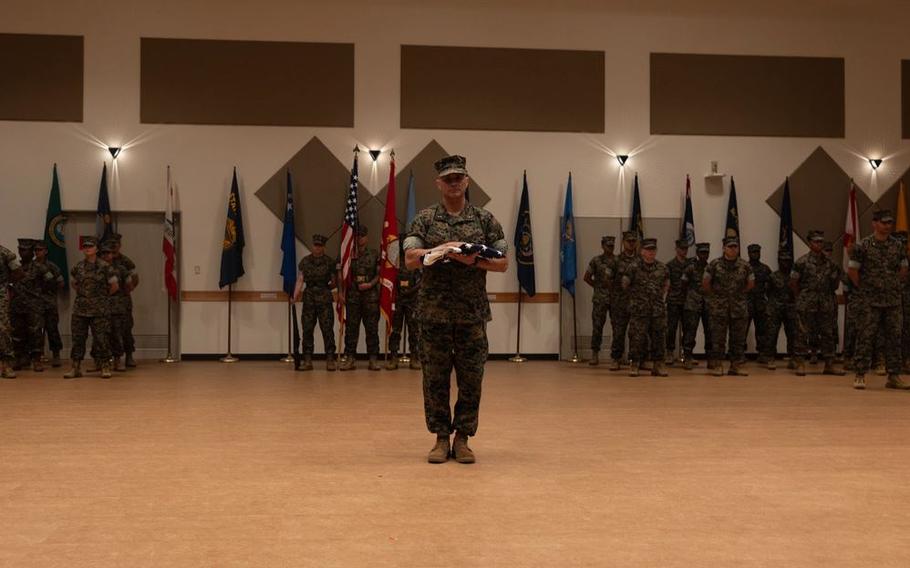Chief Warrant Officer 5 Rene Garcia, director for Installation Personnel Administration Center, Marine Corps Installations Pacific, receives the U.S. flag during his retirement ceremony on Camp Foster, Okinawa.